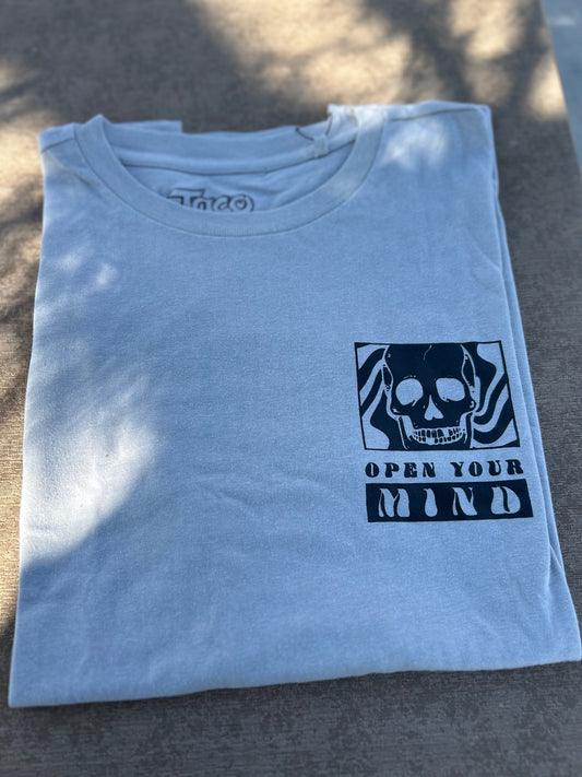 Folded light blue t-shirt with a black graphic and text on a concrete surface